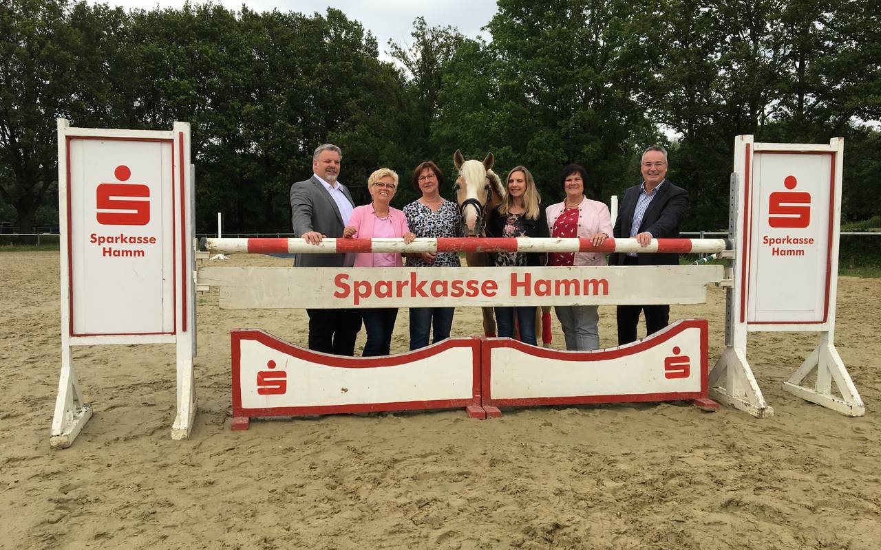 Die Stellvertreterinnen und Stellvertreter der Hammer Sparkasse, des StadtSportBund sowie des Reit- und Fahrverein Pelkum posieren auf dem Reitplatz in Pelkum.