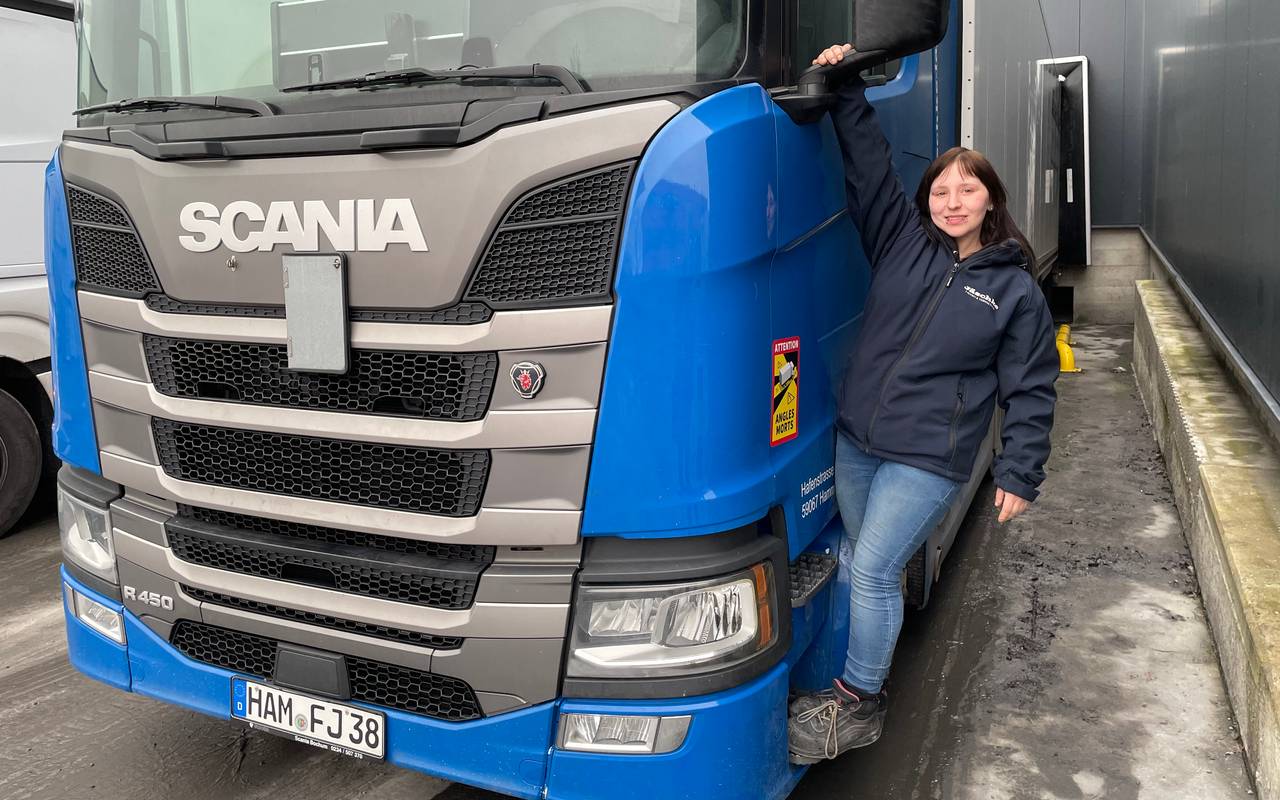 Anika lehnt an einem großen Lkw.