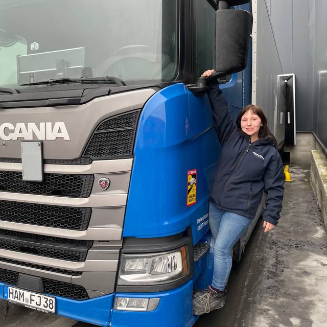 Anika lehnt an einem großen Lkw.