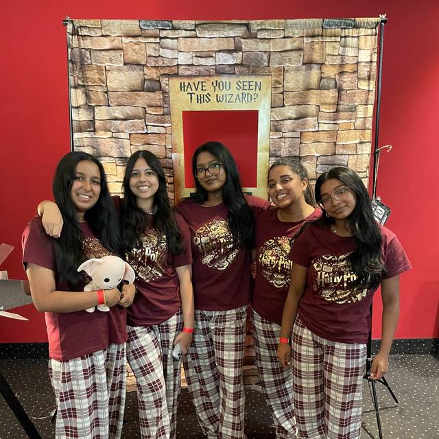 Fünf Mädels stehen in roten Harry-Potter-Schlafanzügen vor eine Fotowand