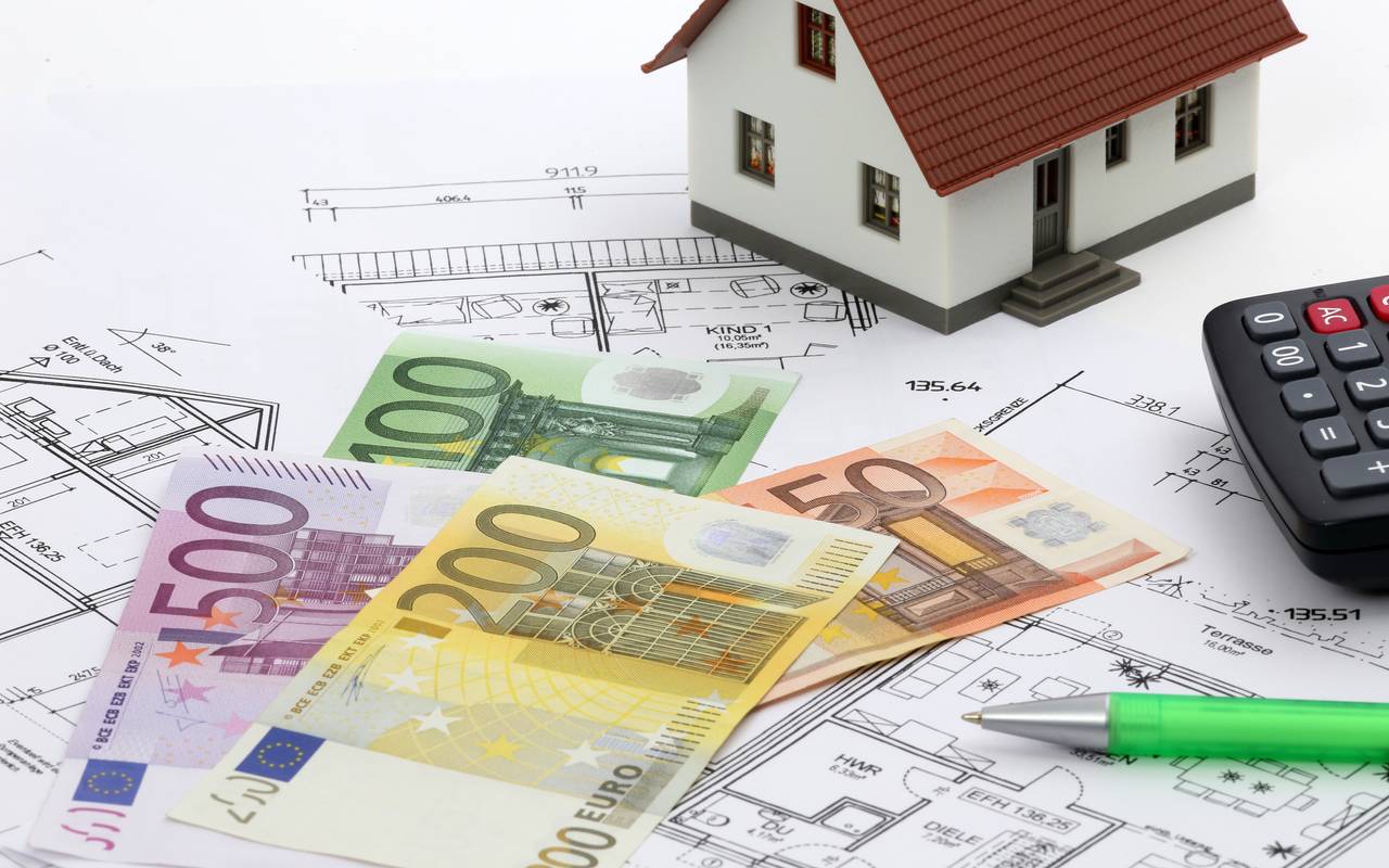 Modellhaus auf Bauplänen und davor Geldscheine