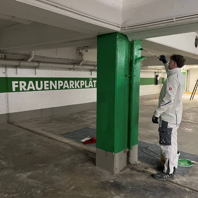 Ein Maler streicht eine Säule in der Tiefgarage unter dem Cineplex.