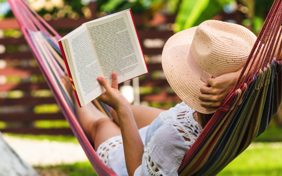 Eine Frau liest ein Buch in einer Hängematte im Garten.