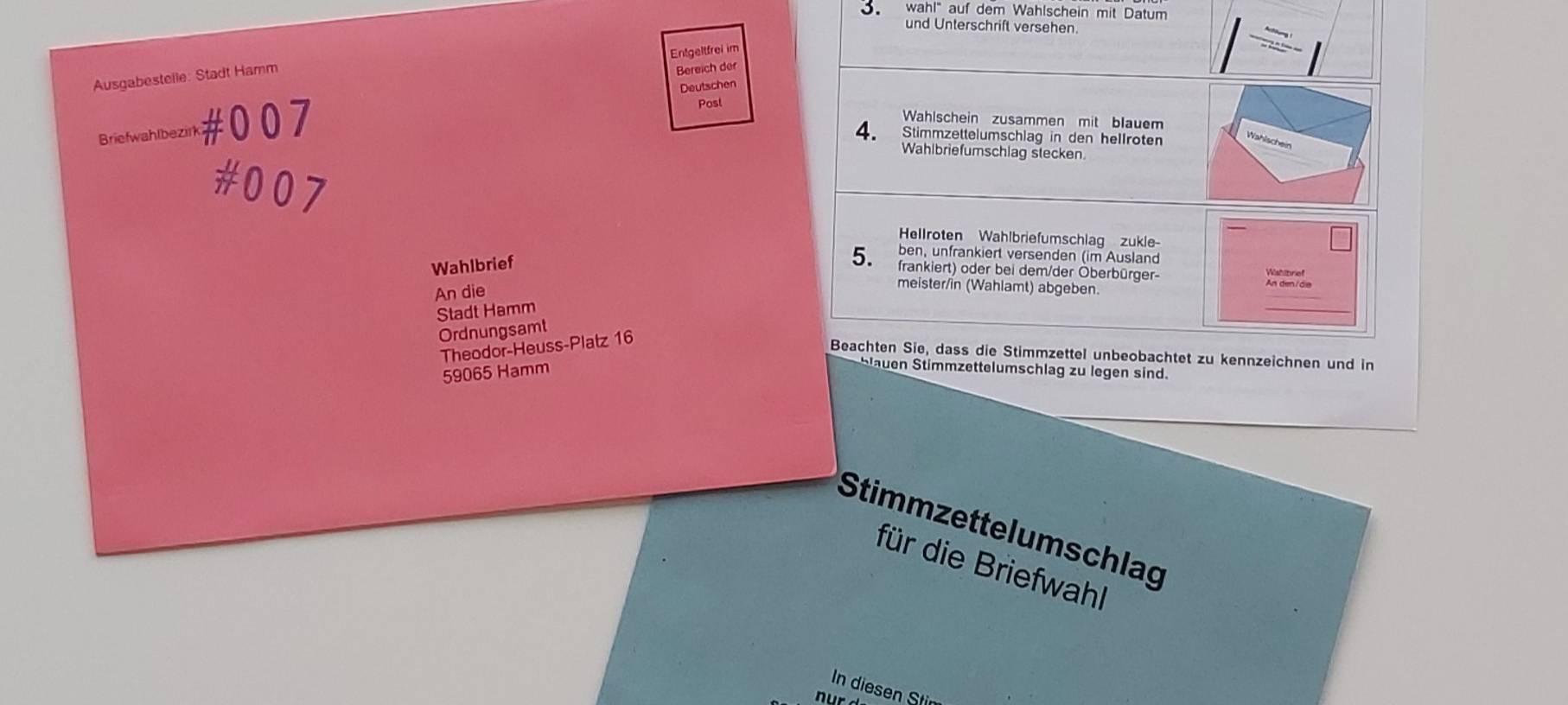 Roter und blauer Briefwahlumschlag und Briefwahlanleitung