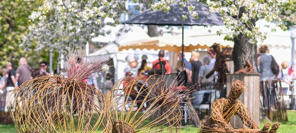 Gartendekoration liegt auf der Wiese. Im Hintergrund stehe Menschen an den Verkaufsständen bei der Landpartie Gut Kump.