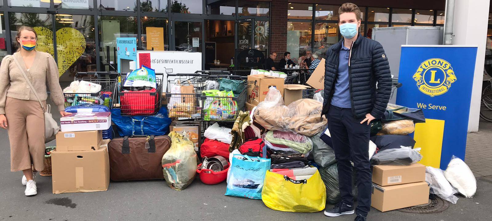 Eine Frau und ein Mann vom Leo Club Hamm stehen vor ihrem Spendenhaufen. Es sind mehrere Einkaufswagen und volle Kisten.