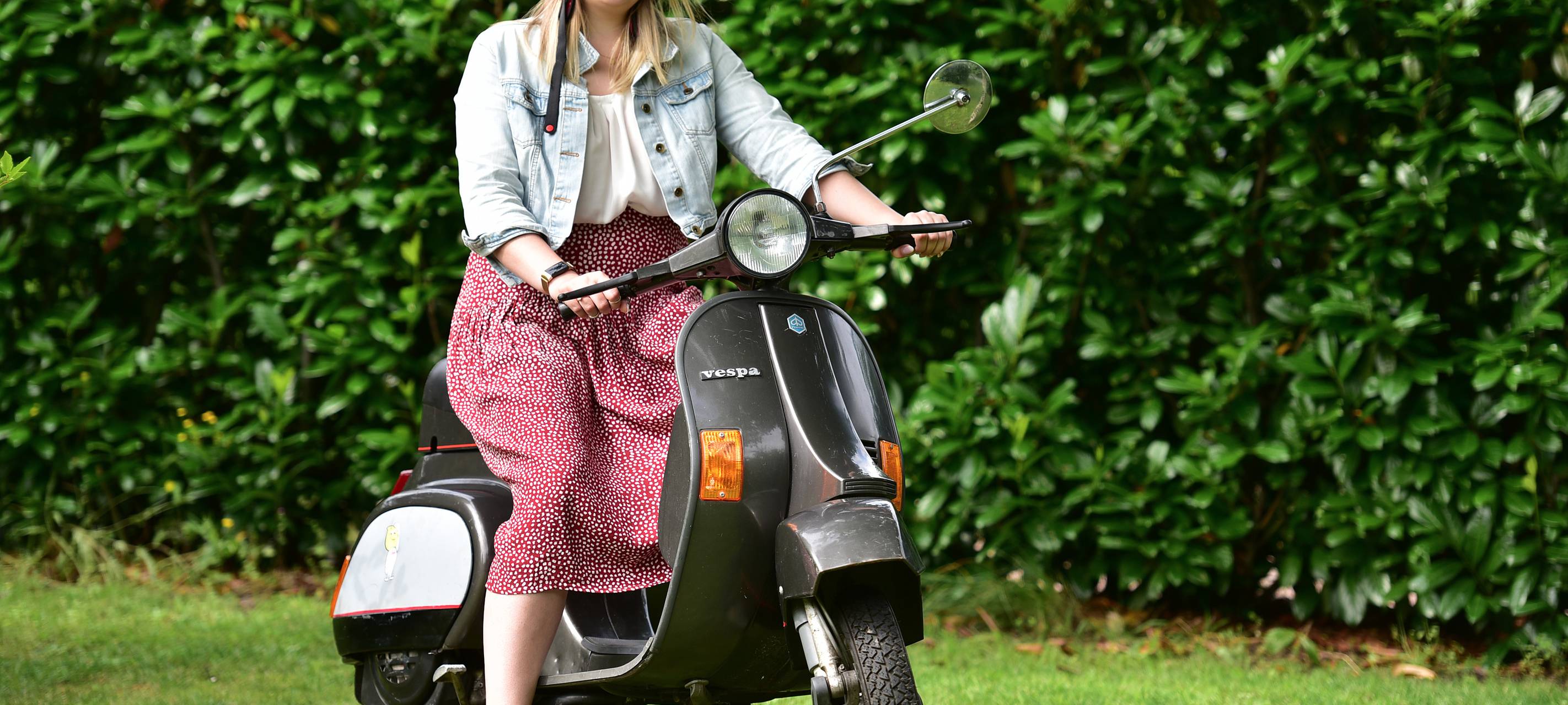 Lippewelle-Reporterin Svenja Jesse sitzt auf einer schwarzes Vespa, die in einem Garten steht.