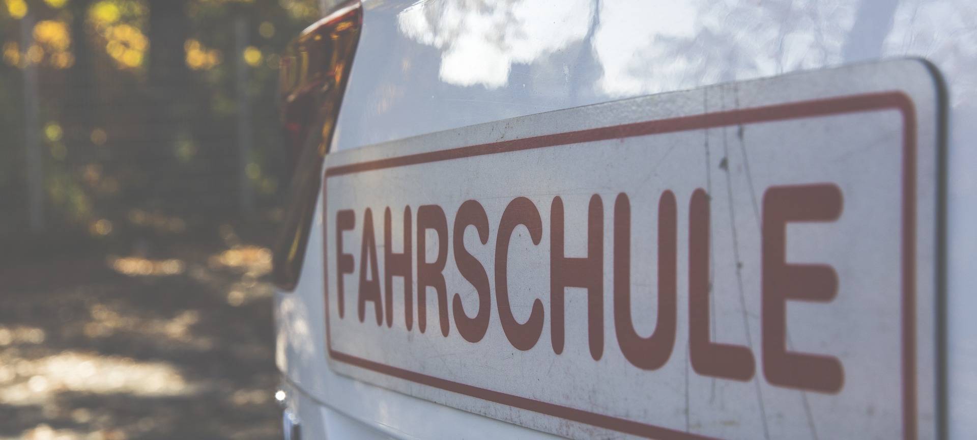 Ein Aufkleber mit der Aufschrift "Fahrschule" an einem weißen Auto.