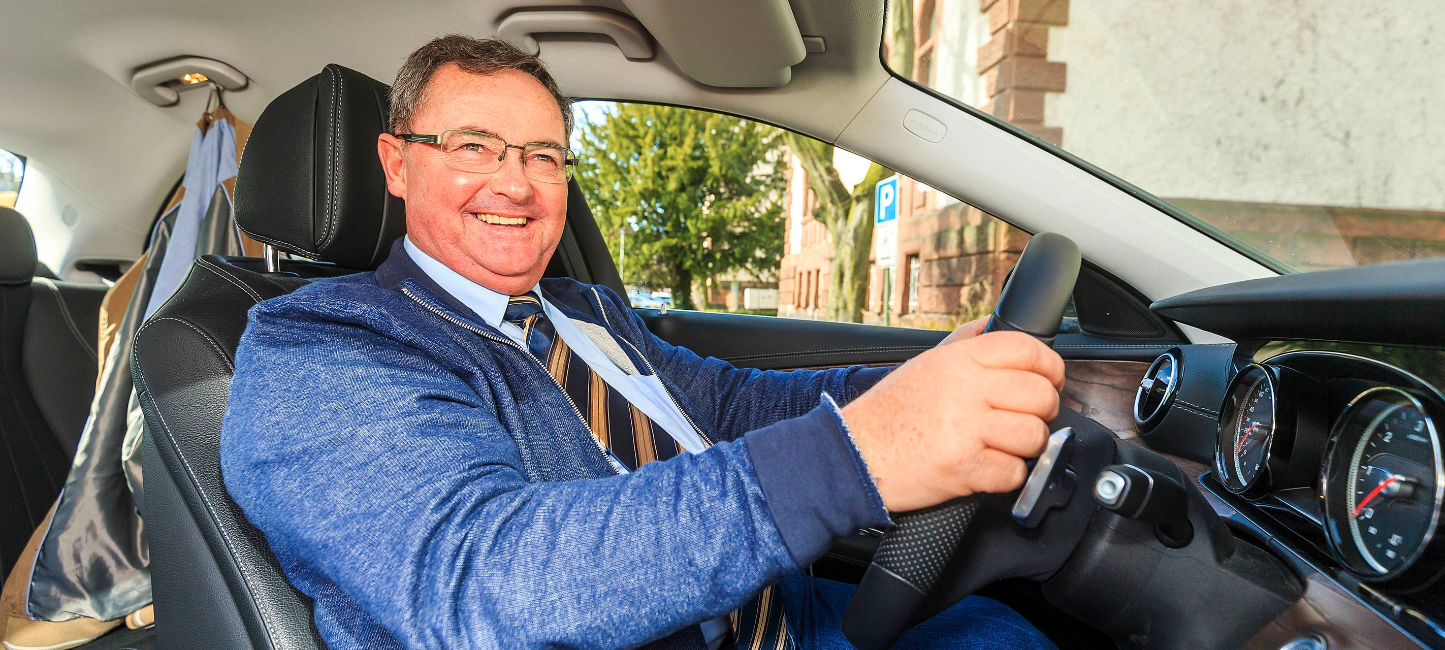 Herbert Jung sitzt im Auto hintern Lenkrad