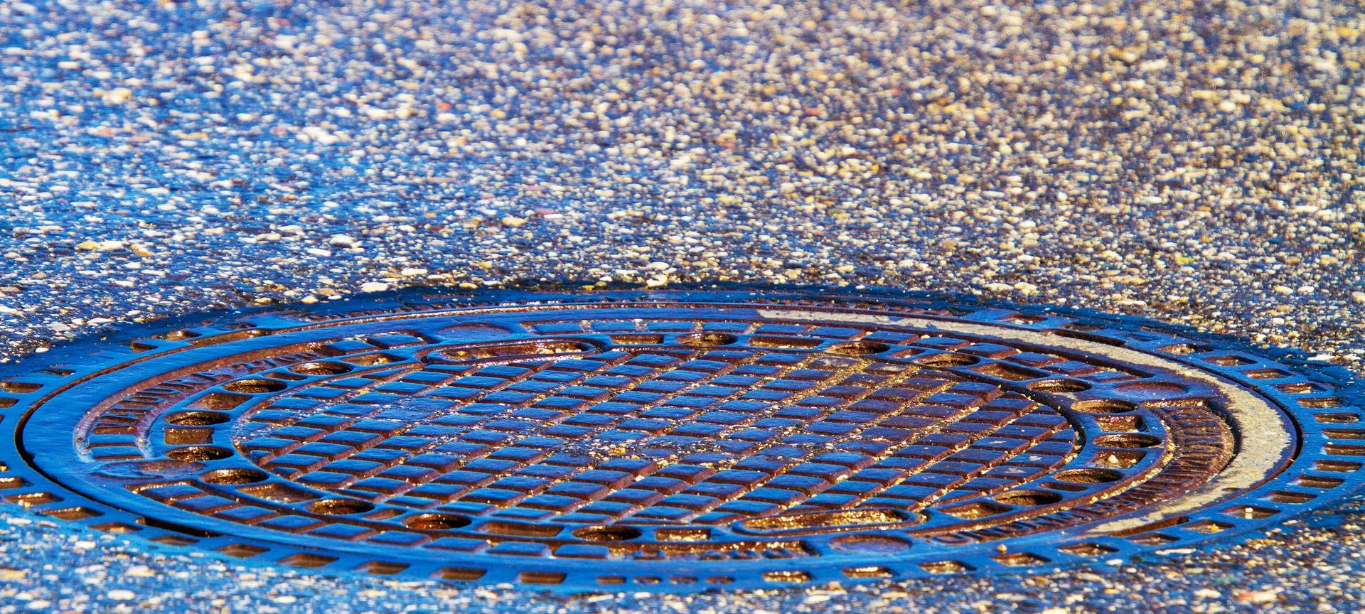 Ein Gullydeckel auf der Straße.