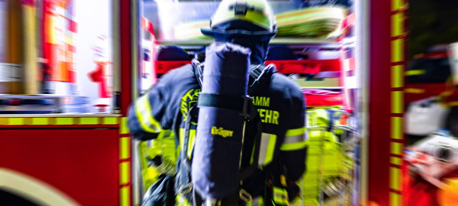 Ein Feuerwehrmann aus Hamm entnimmt einen Schlauchtragekorb. (Symbolfoto)