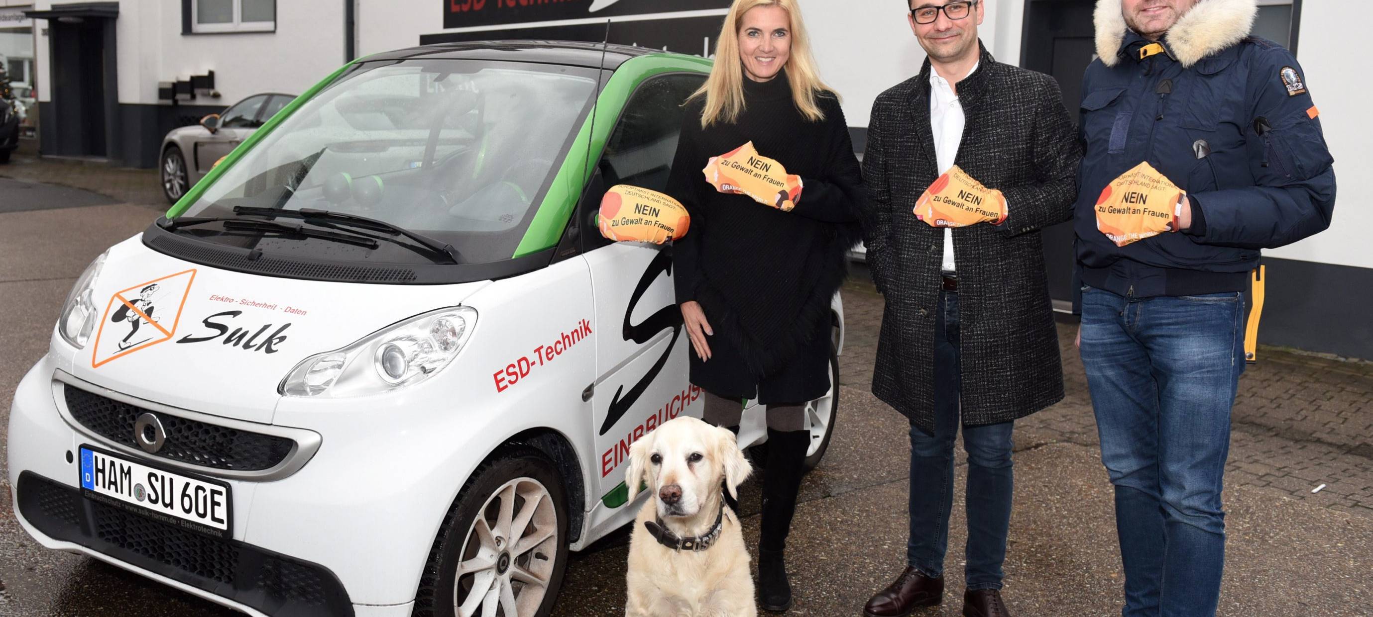 Drei Vertreter der Aktion präsentieren die Spiegelüberzüge vor einem Auto.