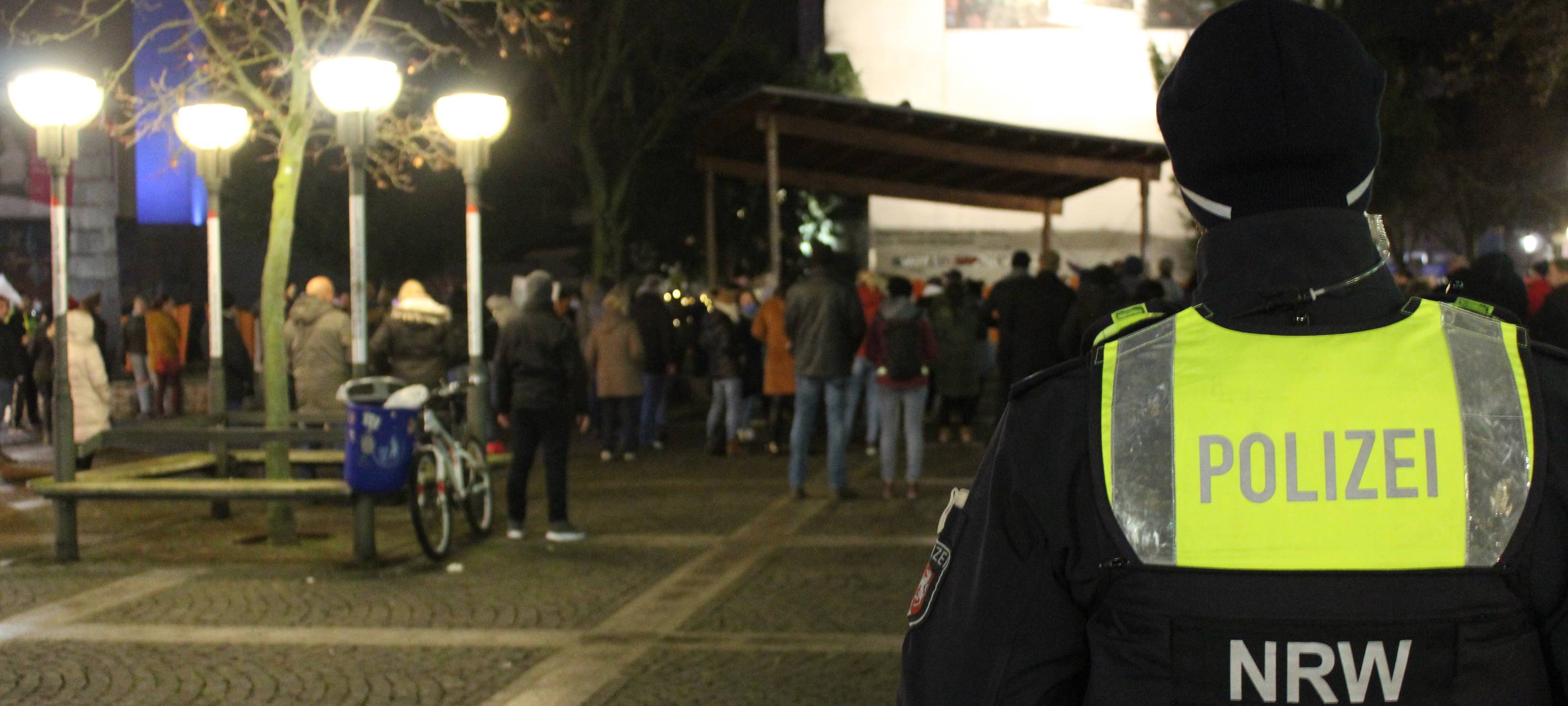 Ein Polizist steht mit dem Rücken zur Kamera vor einer Gruppe Demonstranten.