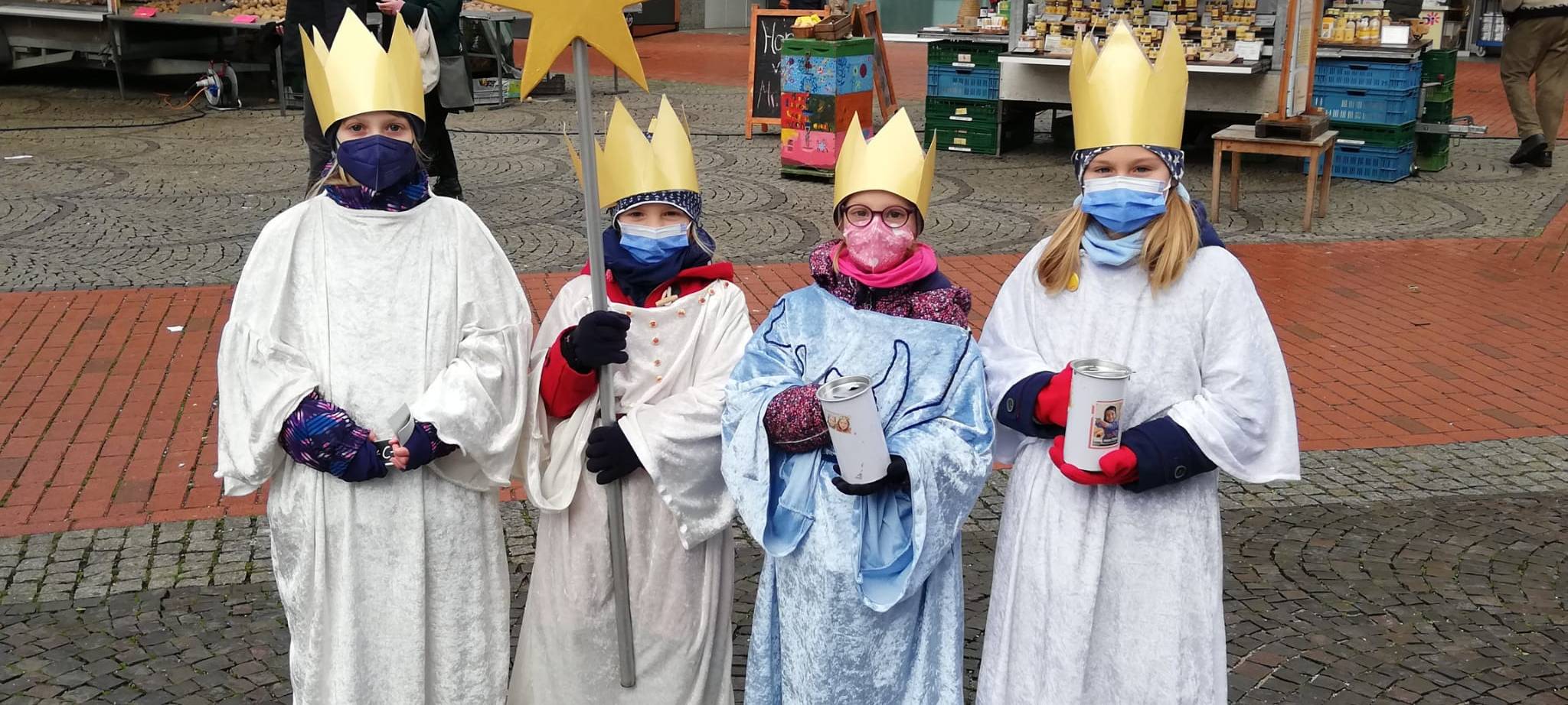 Vier Sternsinger auf dem Marktplatz.