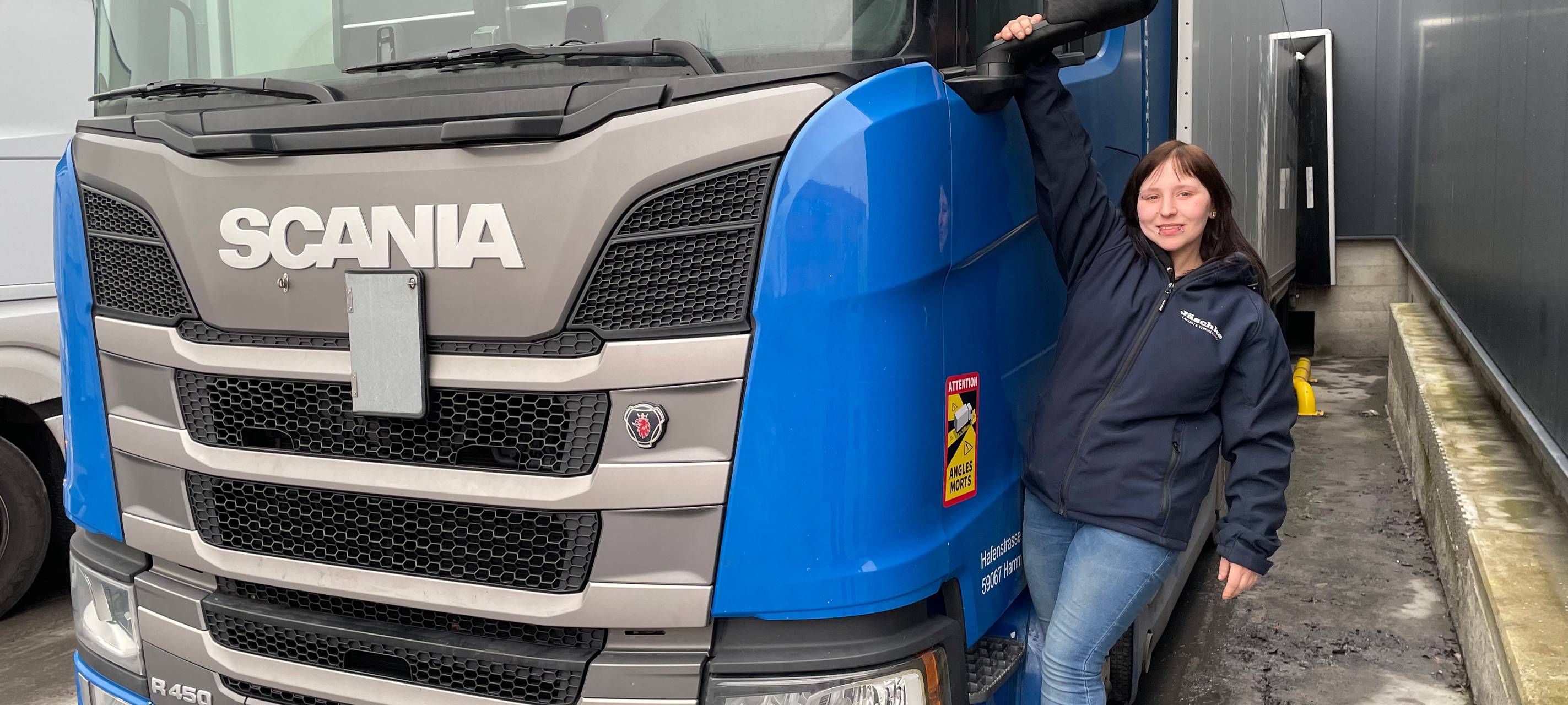 Anika lehnt an einem großen Lkw.