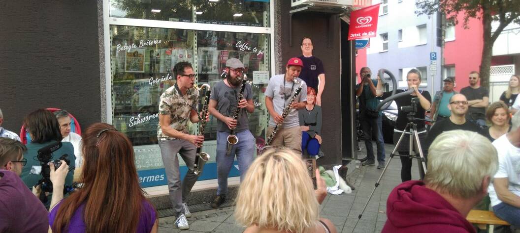 Liveband vor Kioskfenster mit Zuschauern