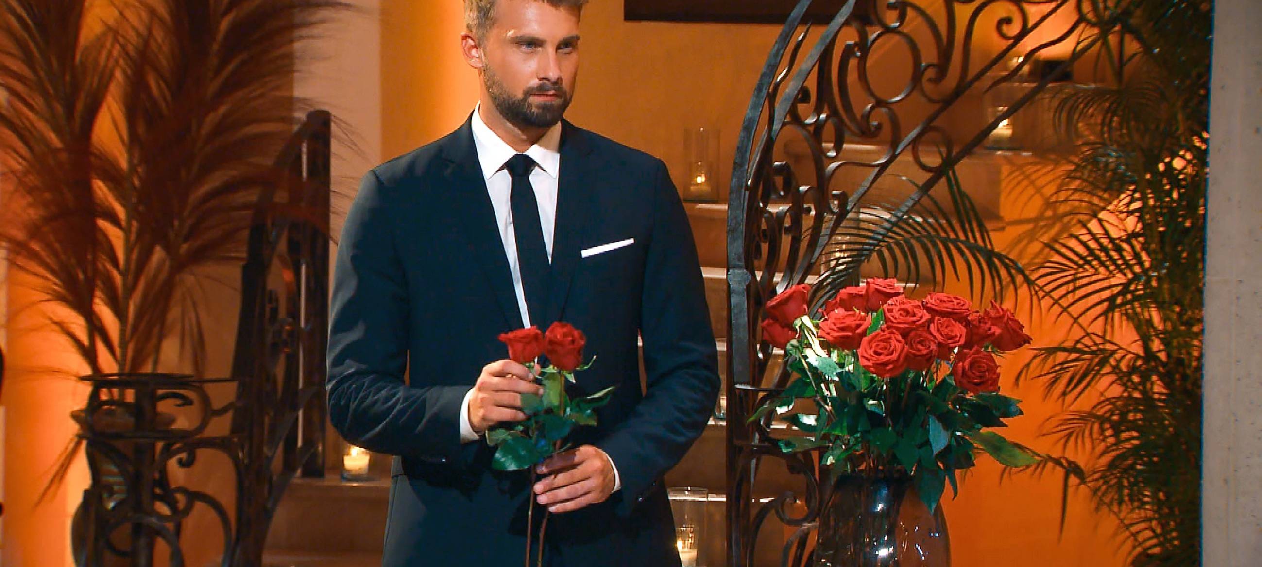 Der neue Bachelor mit einer Rose in der Hand.