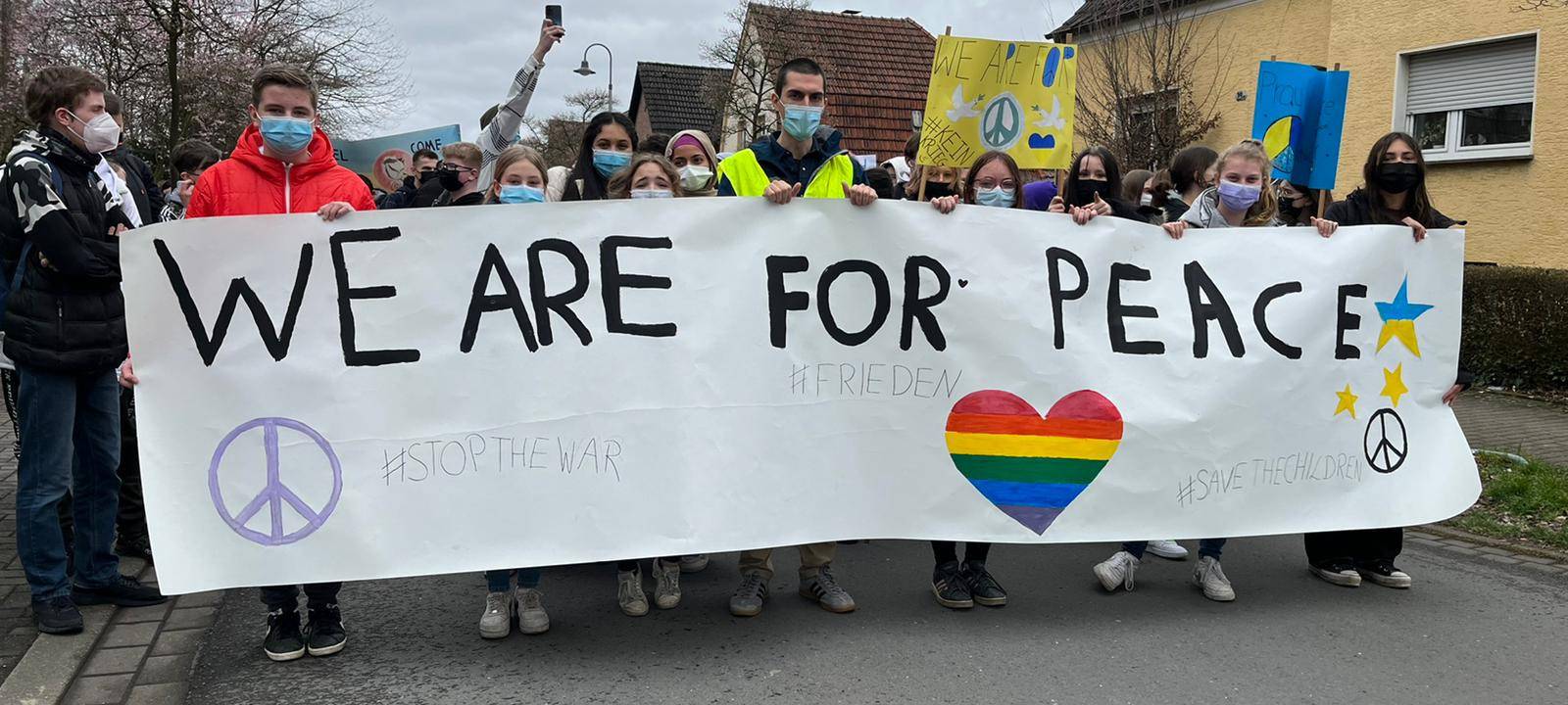 Schüler halten ein Plakat mit der Aufschrift: We are for peace