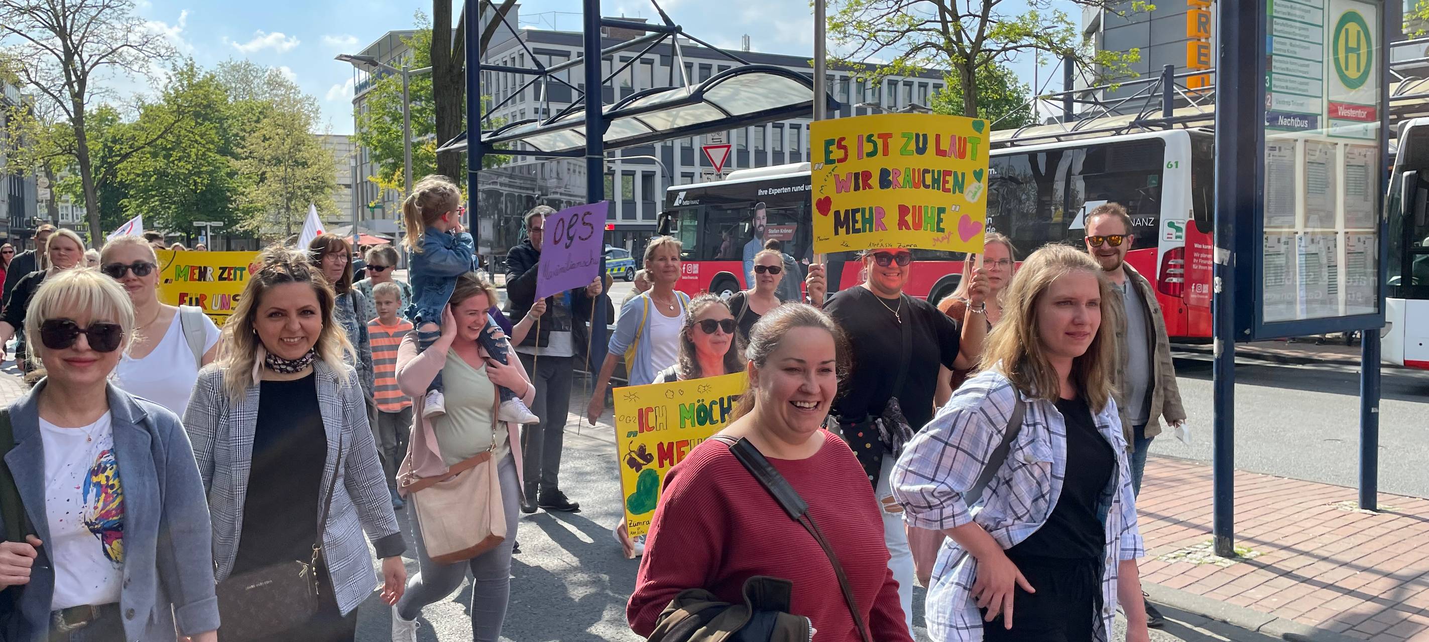 Demonstranten laufen mit Plakaten am Busbahnhof in Hamm vorbei.