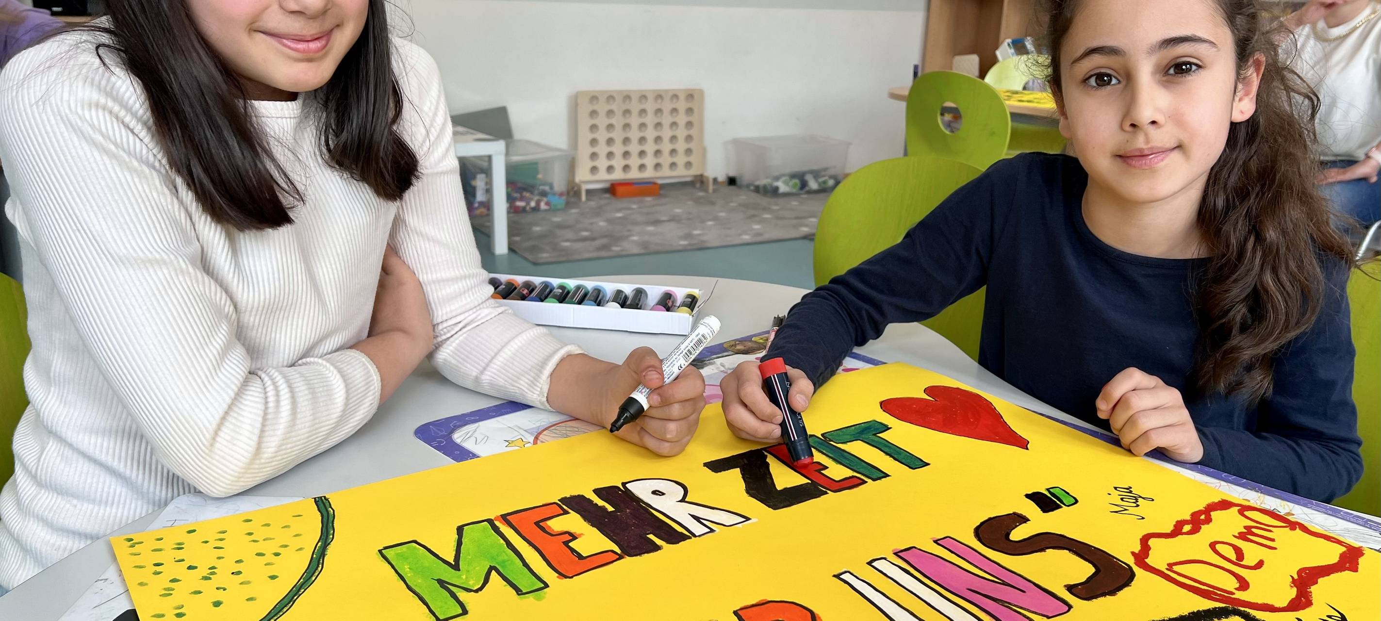 Zwei Kinder bemalen ein Plakat.