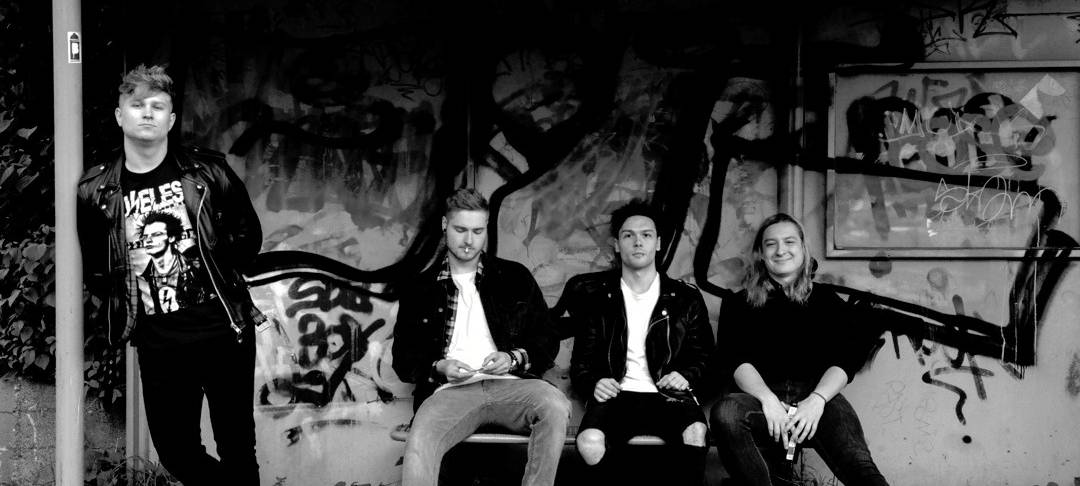 Vier Bandmitglieder vor einer Grafittiwand