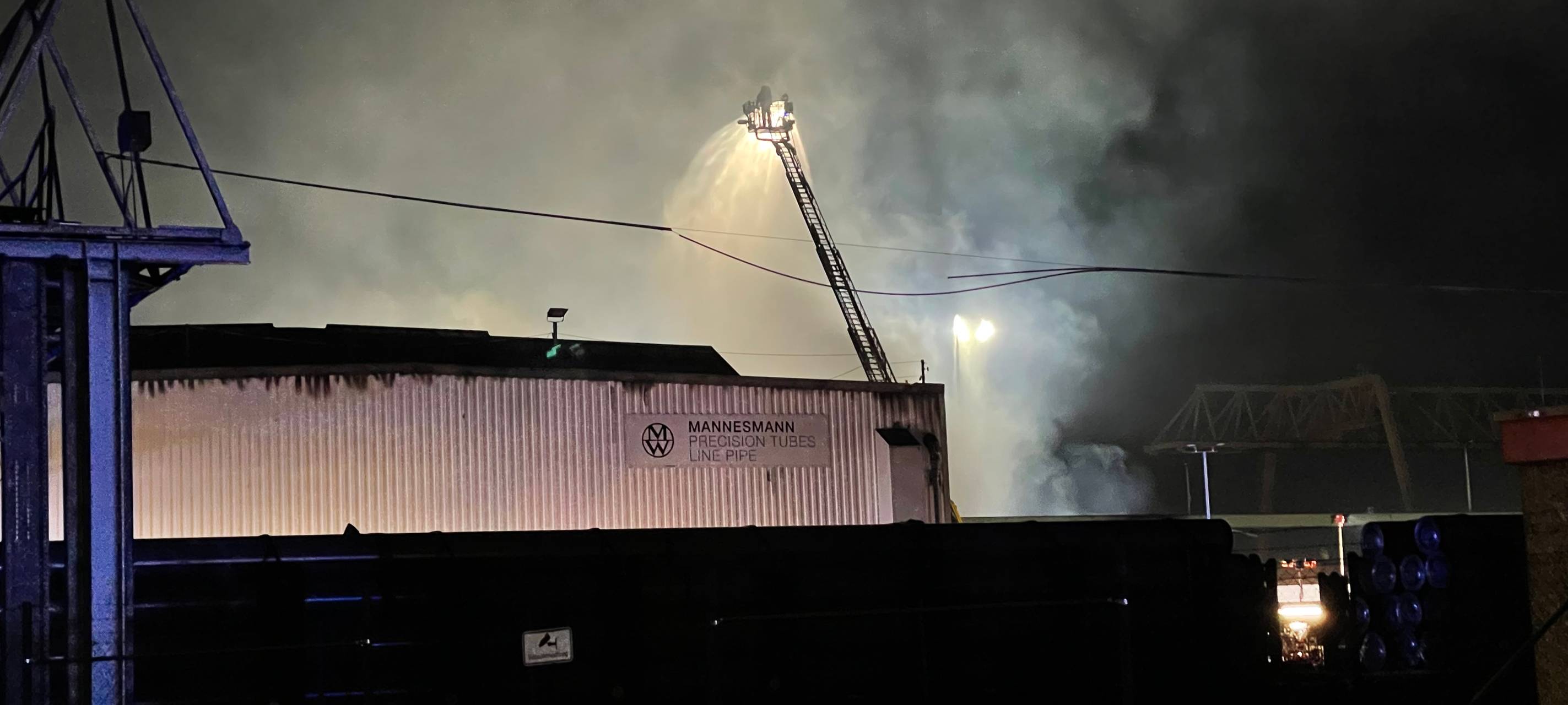 Die Feuerwehr löscht über eine Drehleiter den Brand in der Lagerhalle