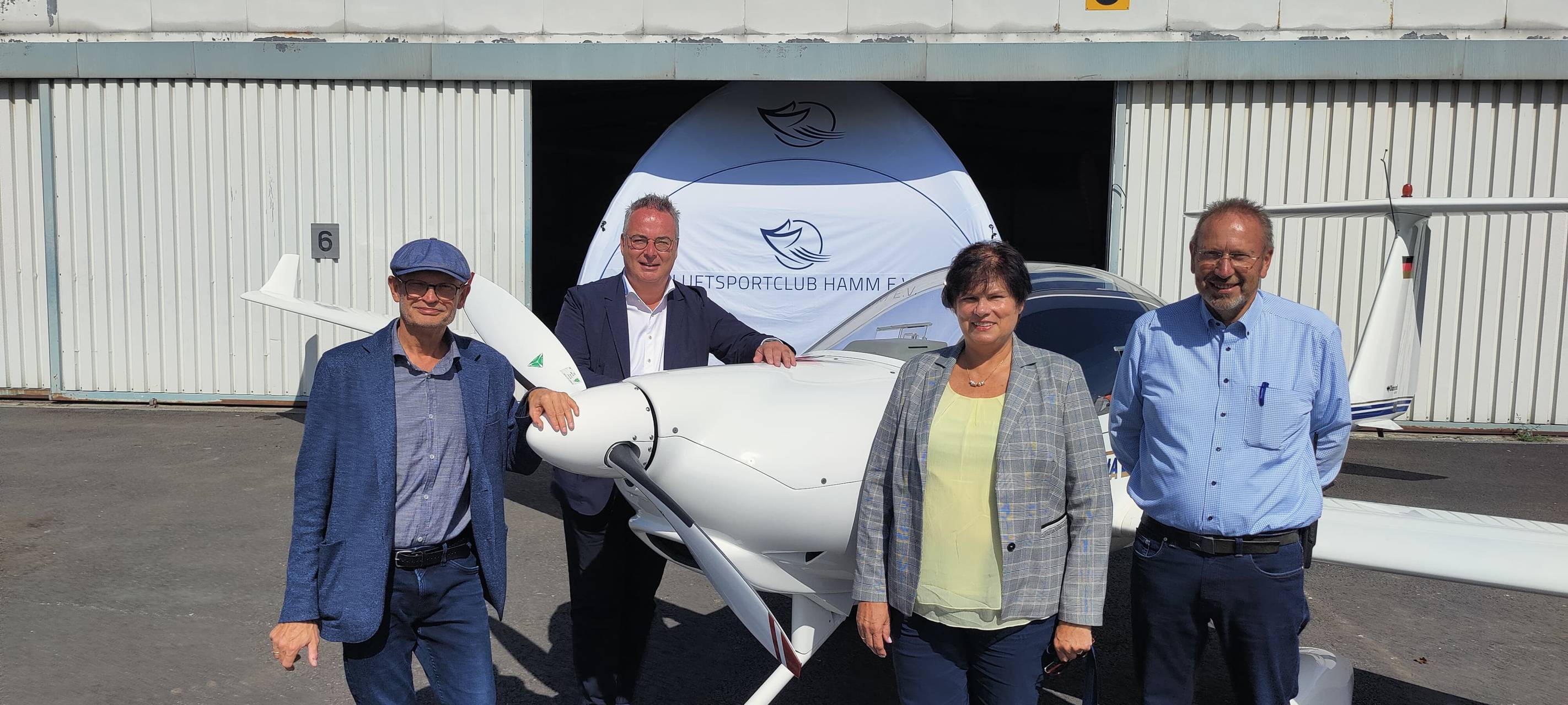 Verantwortliche des Flugplatzes vor einem Flugzeug bei Sonnenschein.