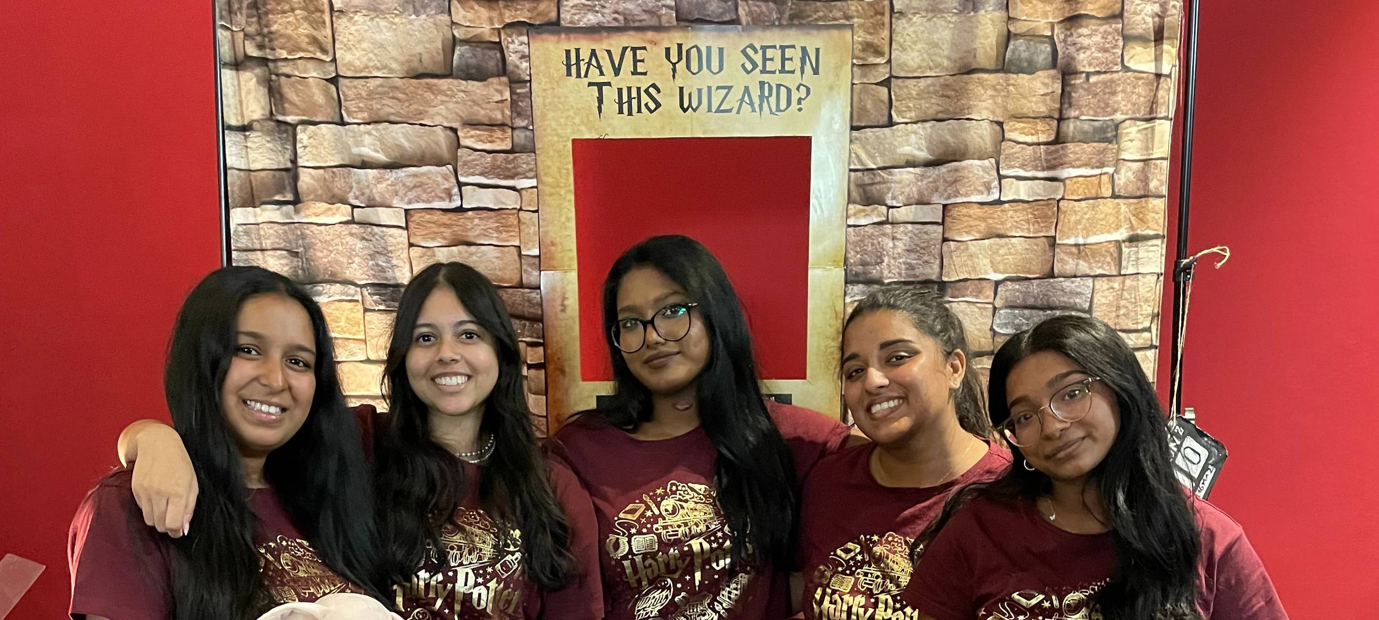 Fünf Mädels stehen in roten Harry-Potter-Schlafanzügen vor eine Fotowand