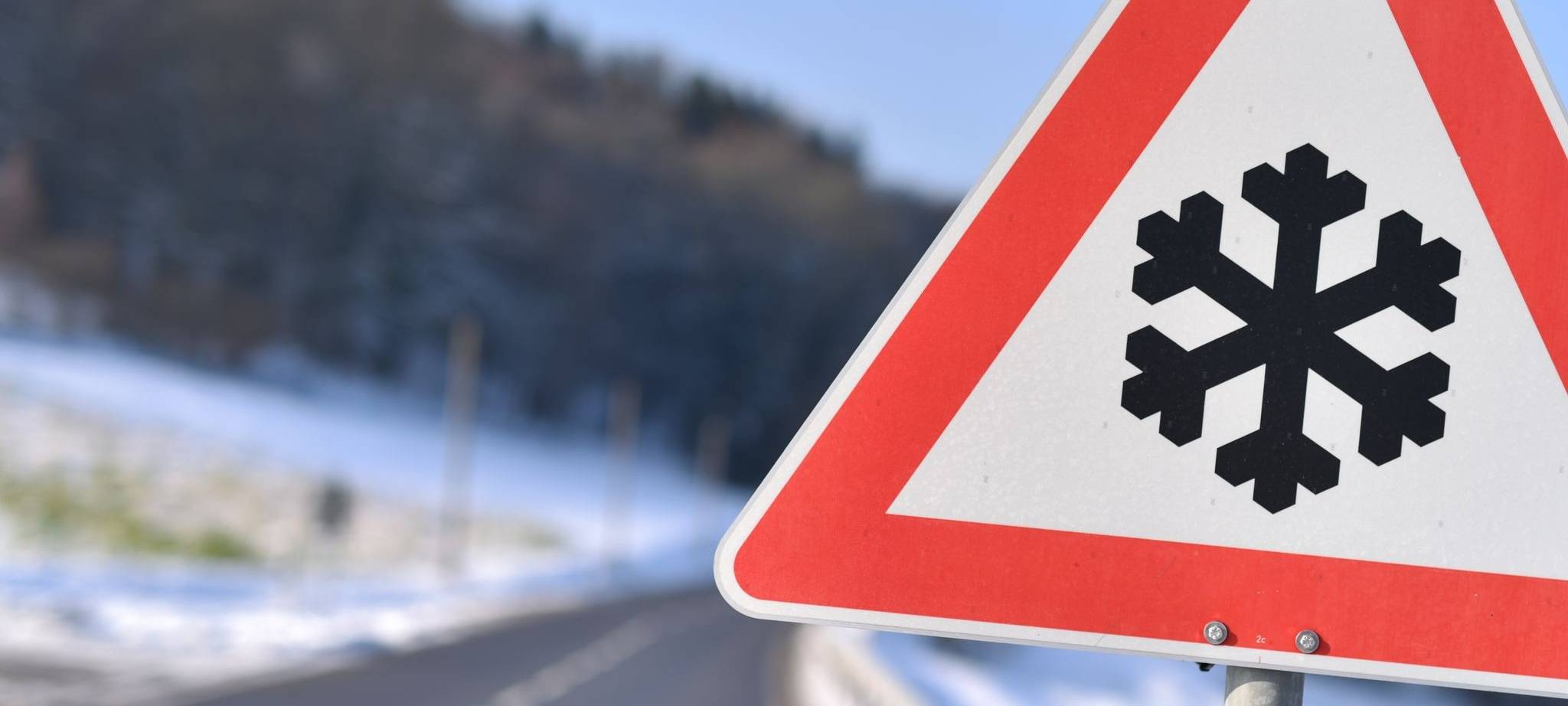 Dieses Warnschild weist auf einer Straße auf Straßenglätte hin.