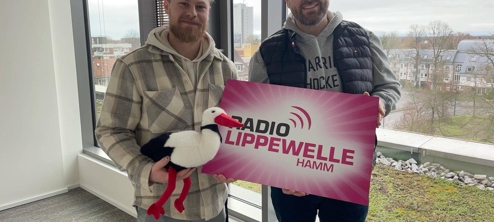 Zwei "Hammer Eisbären" stehen vor einem Fenster und lächeln.