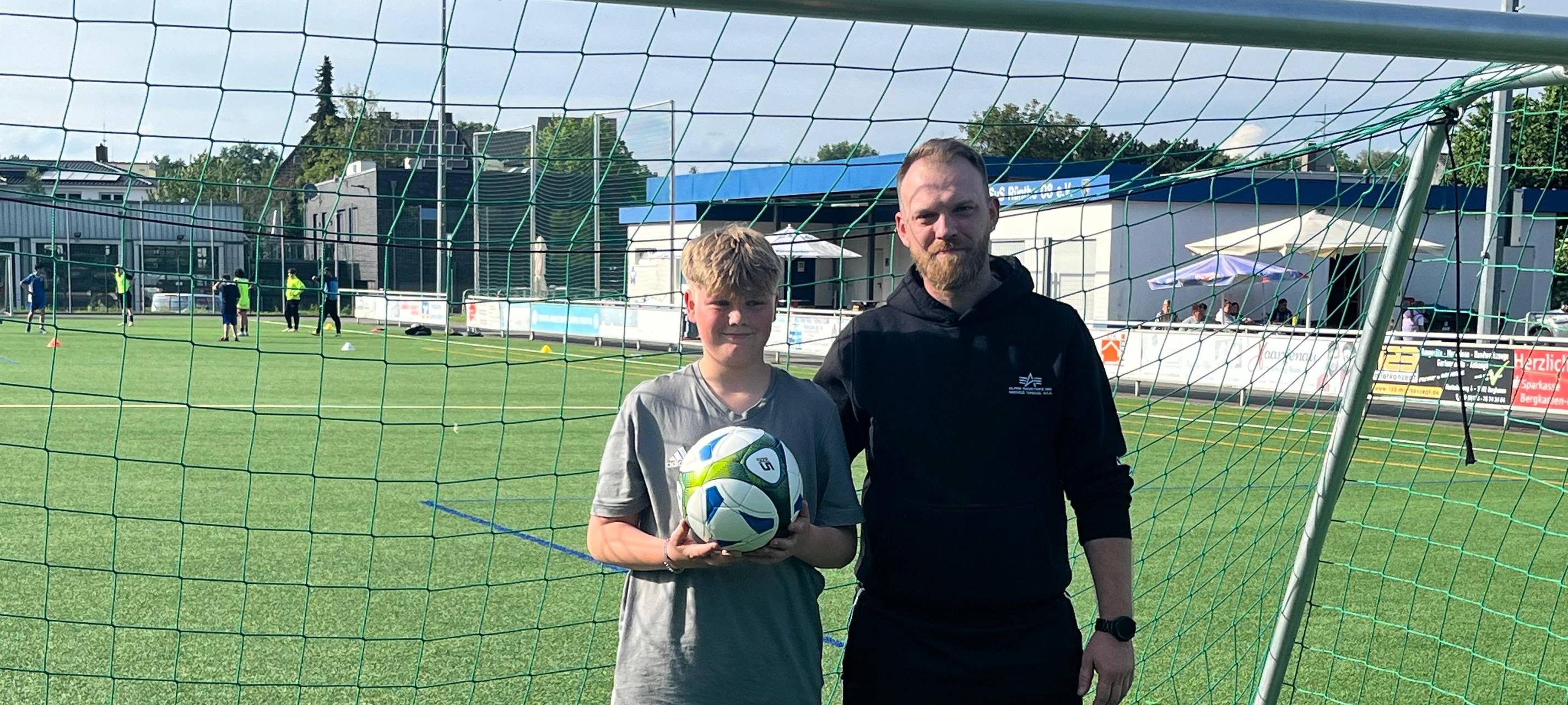 Jayden zusammen mit seinem Trainer auf dem Spielfeld