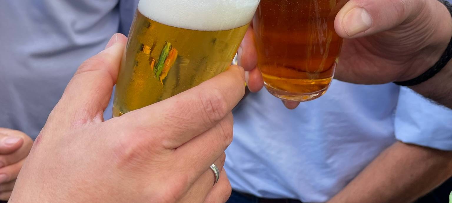 Menschen stoßen mit Bier an.