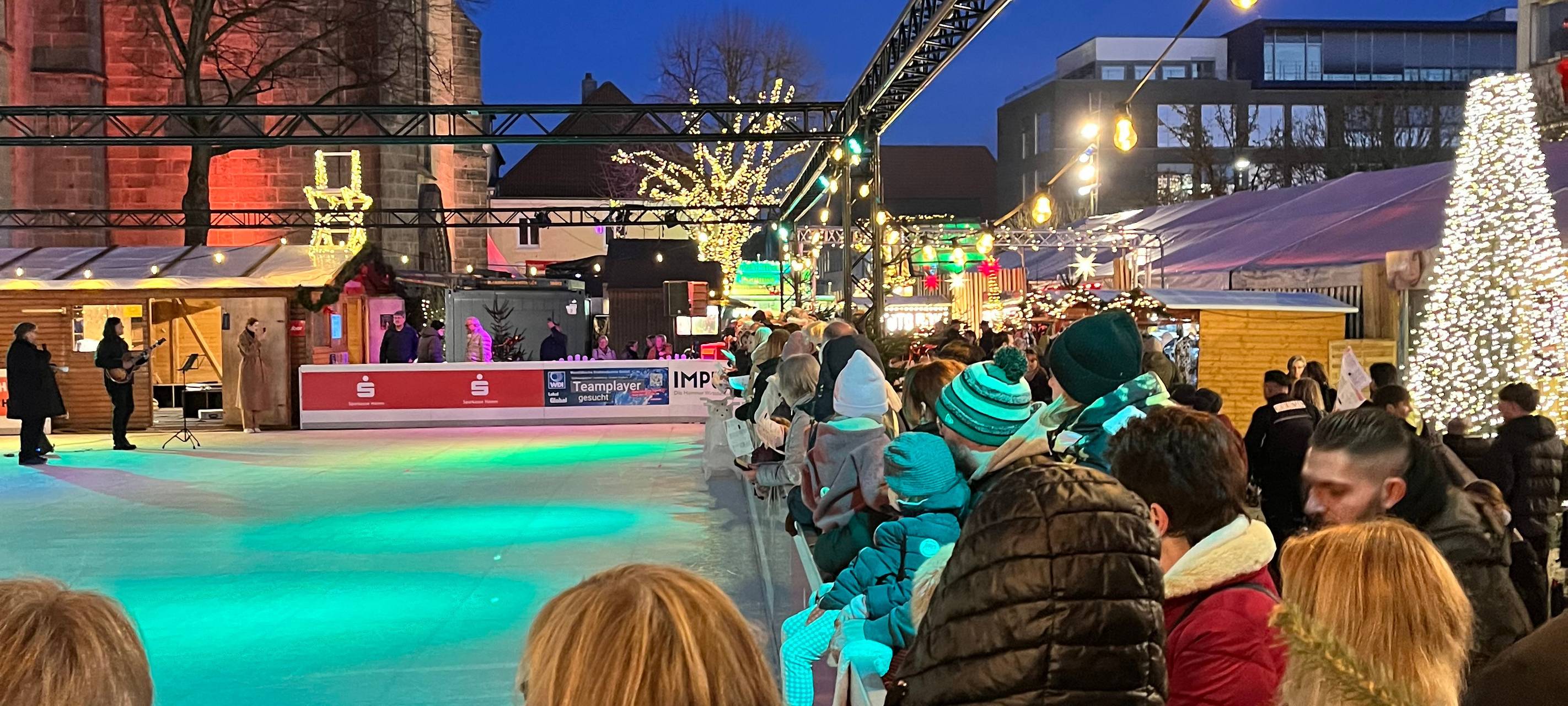 Singende Menschen rund um die Eisfläche auf dem Hammer Weihnachtsmarkt.