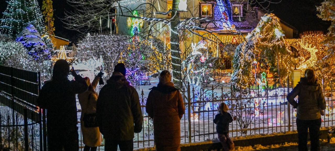 Schaulustige stehen vor dem weihnachtlich hell beleuchteten Garten der Familie Muschner in Ostbrandenburg