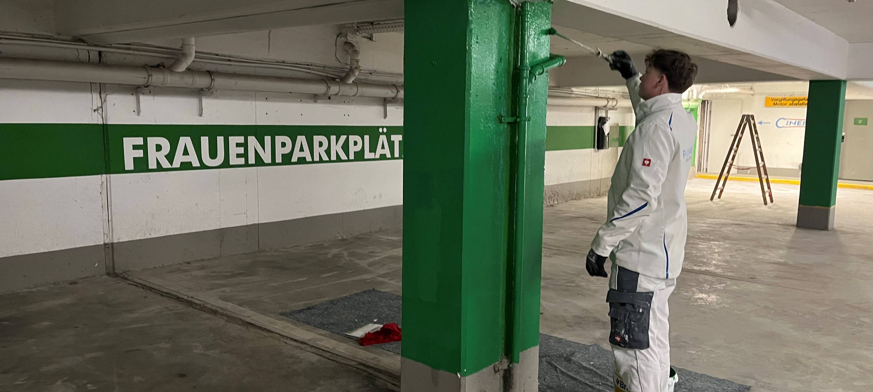 Ein Maler streicht eine Säule in der Tiefgarage unter dem Cineplex.