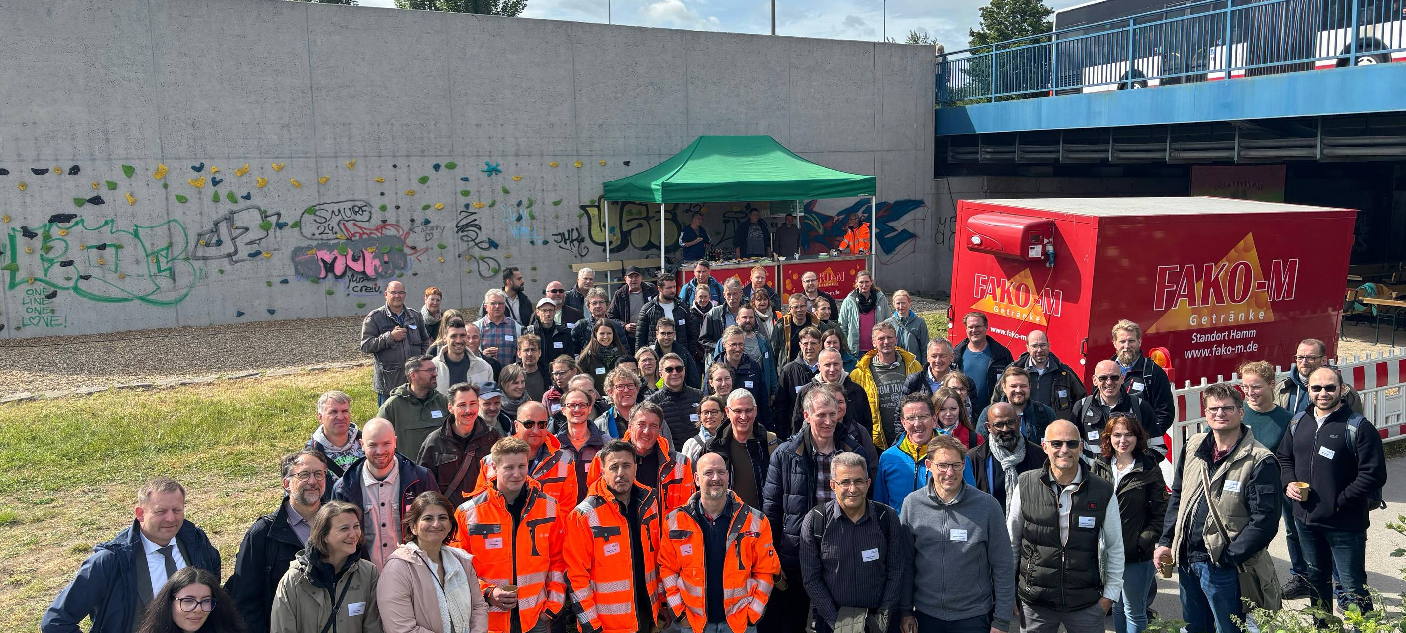 Eine große Gruppe Ingenieure posiert vor einer Brücke.