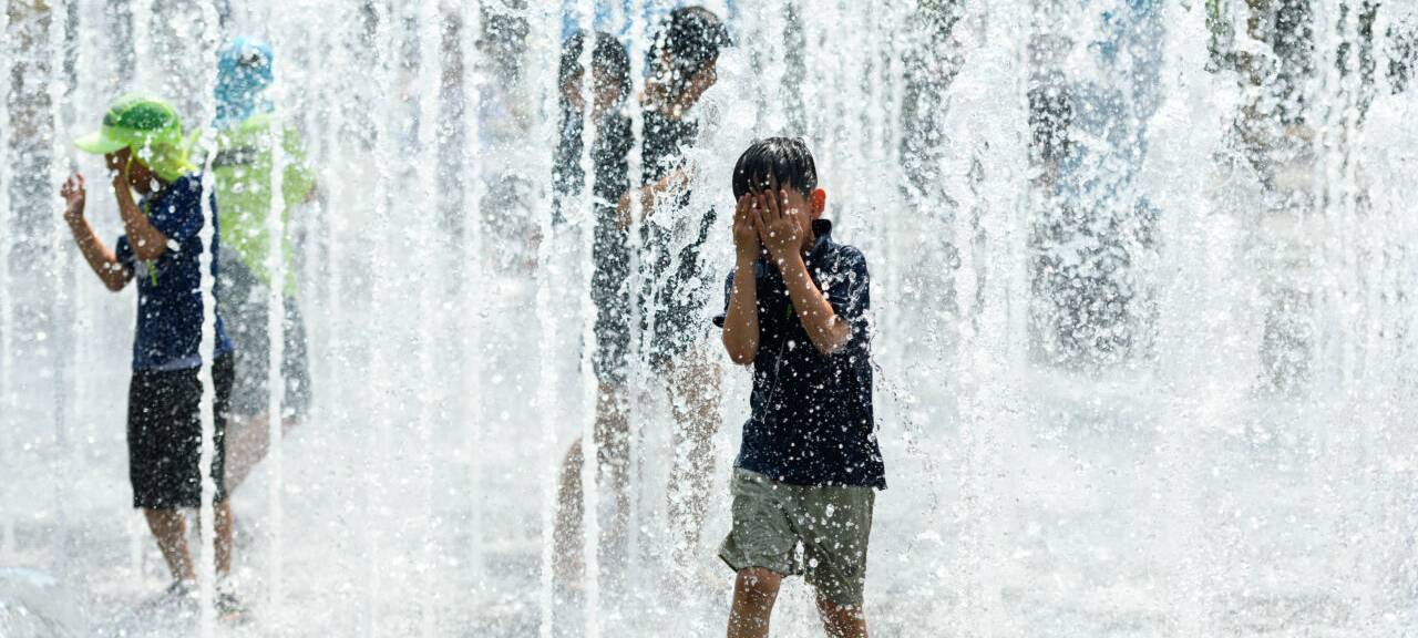 Kinder spielen an einem heißen Nachmittag in einem Springbrunnen auf dem Platz im Wasser.