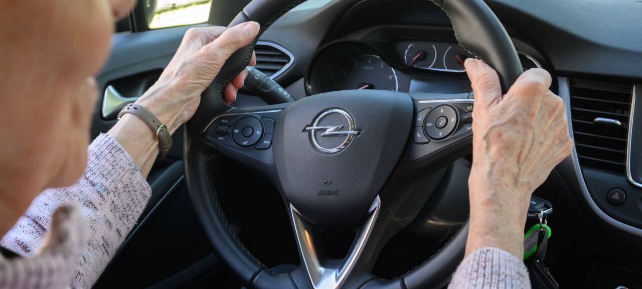 Eine ältere Autofahrerin sitzt am Steuer.