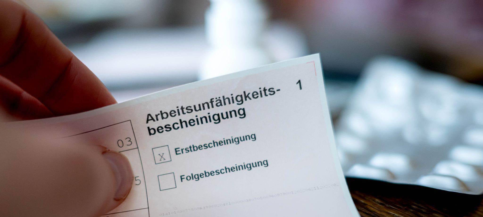 Eine Person hält eine Arbeitsunfähigkeitsbescheinigung