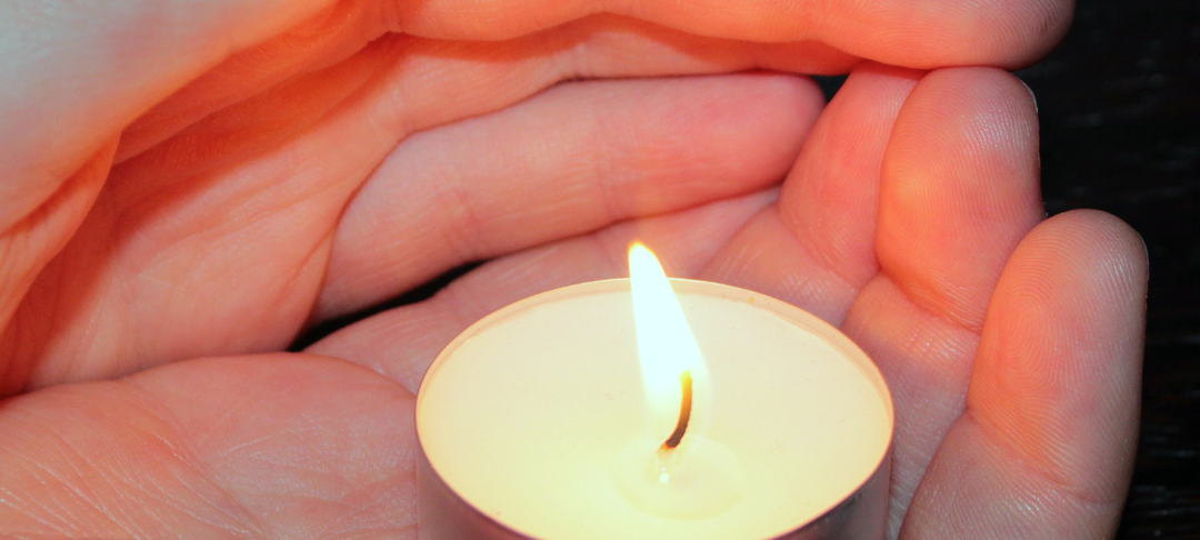Ein Teelicht in einer Hand.
