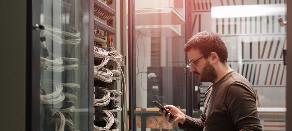 Ein Techniker sitzt vor einem Serverschrank und behebt ein technisches Problem.