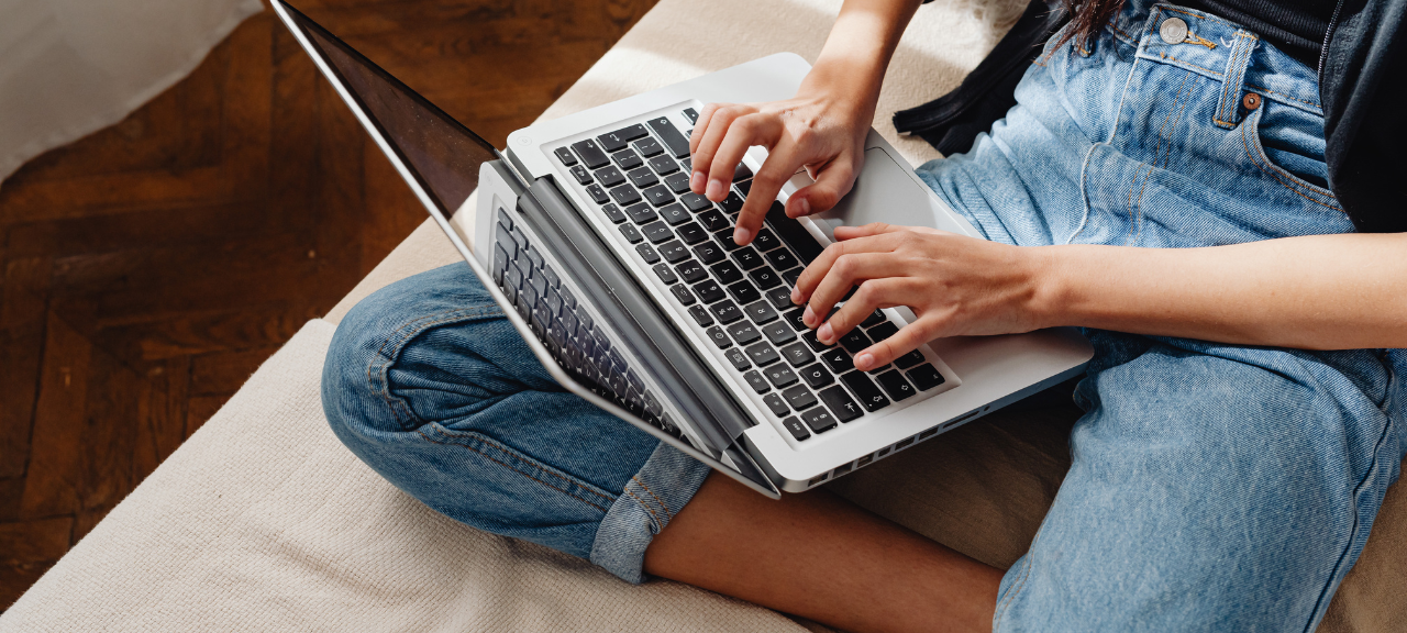 Eine Frau surft an ihrem Laptop auf der Couch.