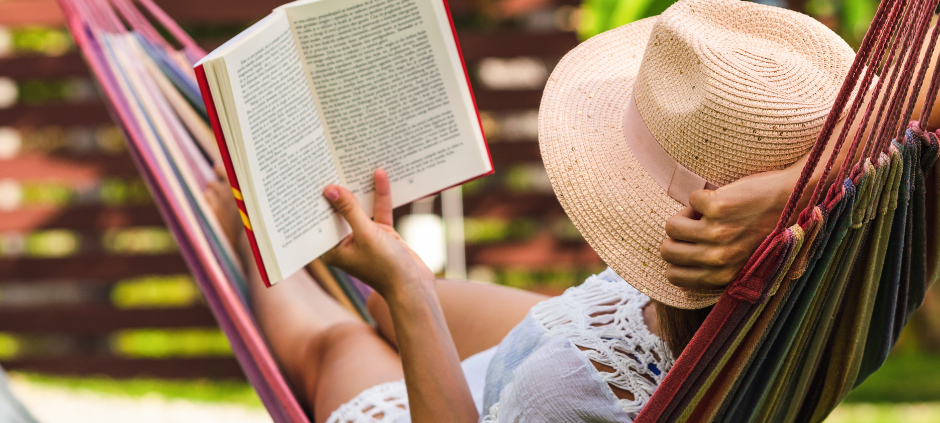 Eine Frau liest ein Buch in einer Hängematte im Garten.
