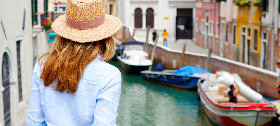 Eine Frau lehnt in Venedig an einem Brückengeländer.