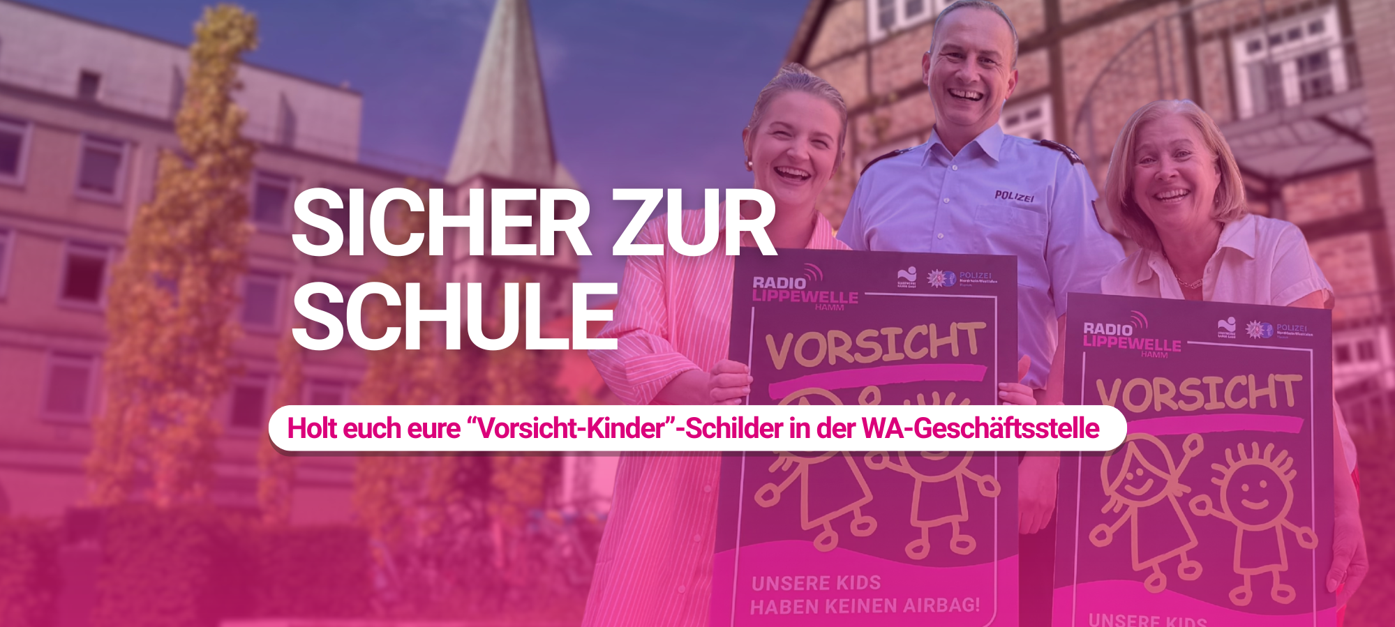 Zwei Frauen und ein Polizist in Uniform stehen lachend vor einem Fachwerkgebäude in der Hammer Innenstadt und halten je ein pinkes "Vorsicht - Unsere Kids haben keinen Airbag!"-Schild von Radio Lippewelle Hamm in die Höhe. Im Bild der Text: "Sicher zur Schule - Holt euch eure Vorsicht-Kinder-Schilder in der WA-Geschäftsstelle".